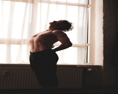 man doing light morning movement beside a window